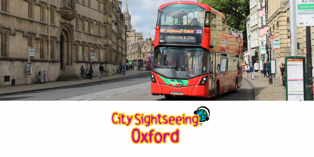 City Sightseeing Oxford logo sites beneath one of their striking double-deckers departing a stop at High Street, Oxford